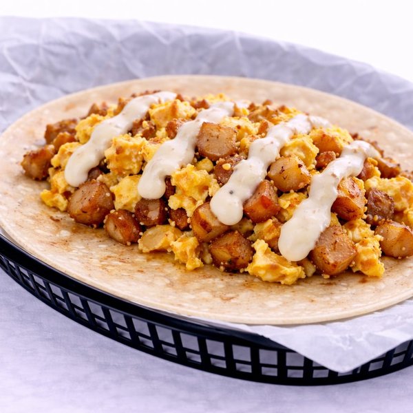 Potato and scrambled egg breakfast taco topped with queso on a flour tortilla