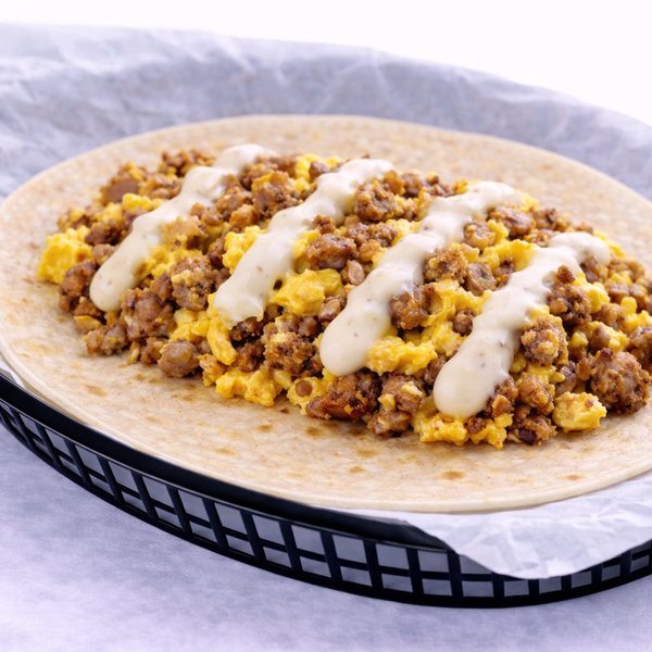 Sausage and scrambled egg breakfast taco topped with queso on a flour tortilla